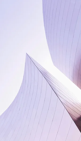 Two curved concrete surfaces meeting, lit pink and lilac